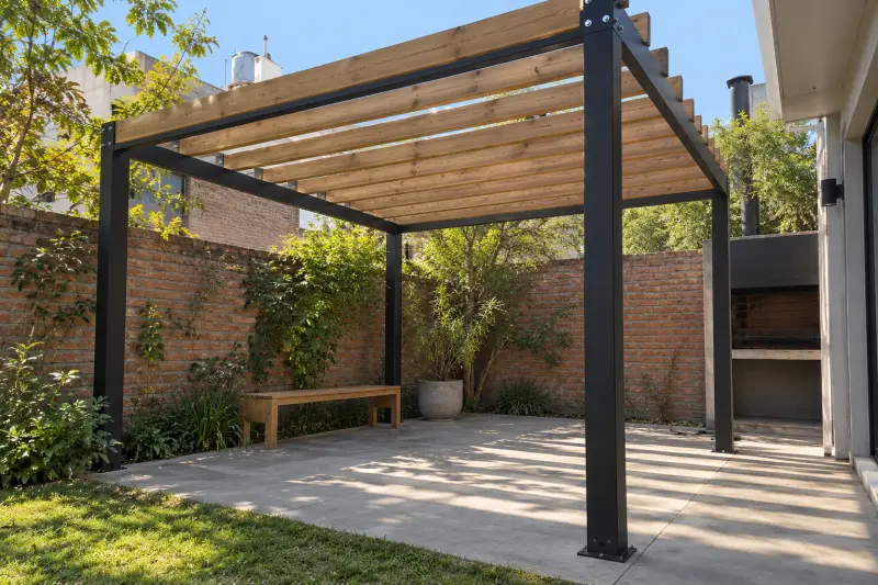 Pérgola de hierro negro y madera en un patio